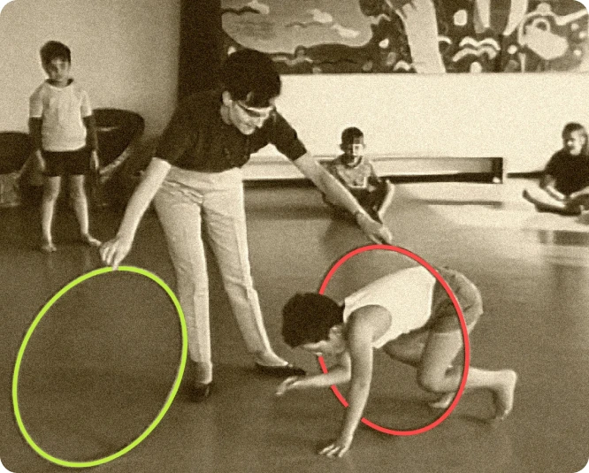 A woman holding two hula-hoops and a child passing through one of them.
