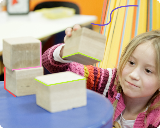 A little girl creating a tower with wooden blocks